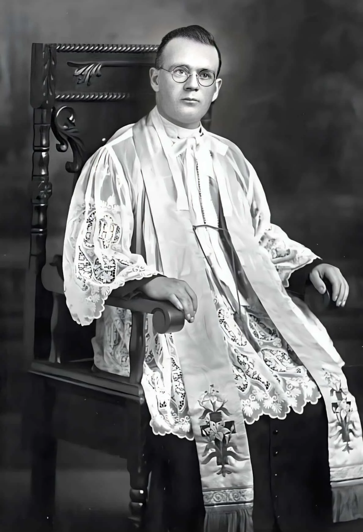 Father Arthur Gallant in priestly vestments, seated in an armchair