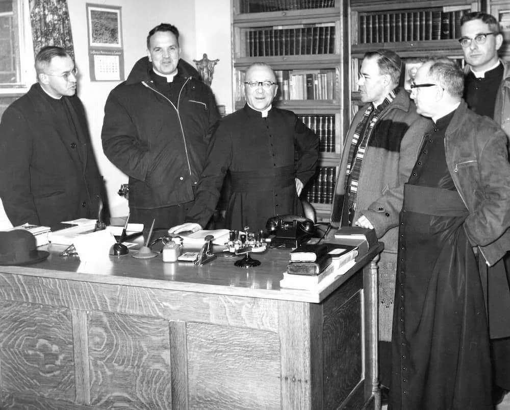 Bishop Couturier and the visiting group gathered in a construction-site office